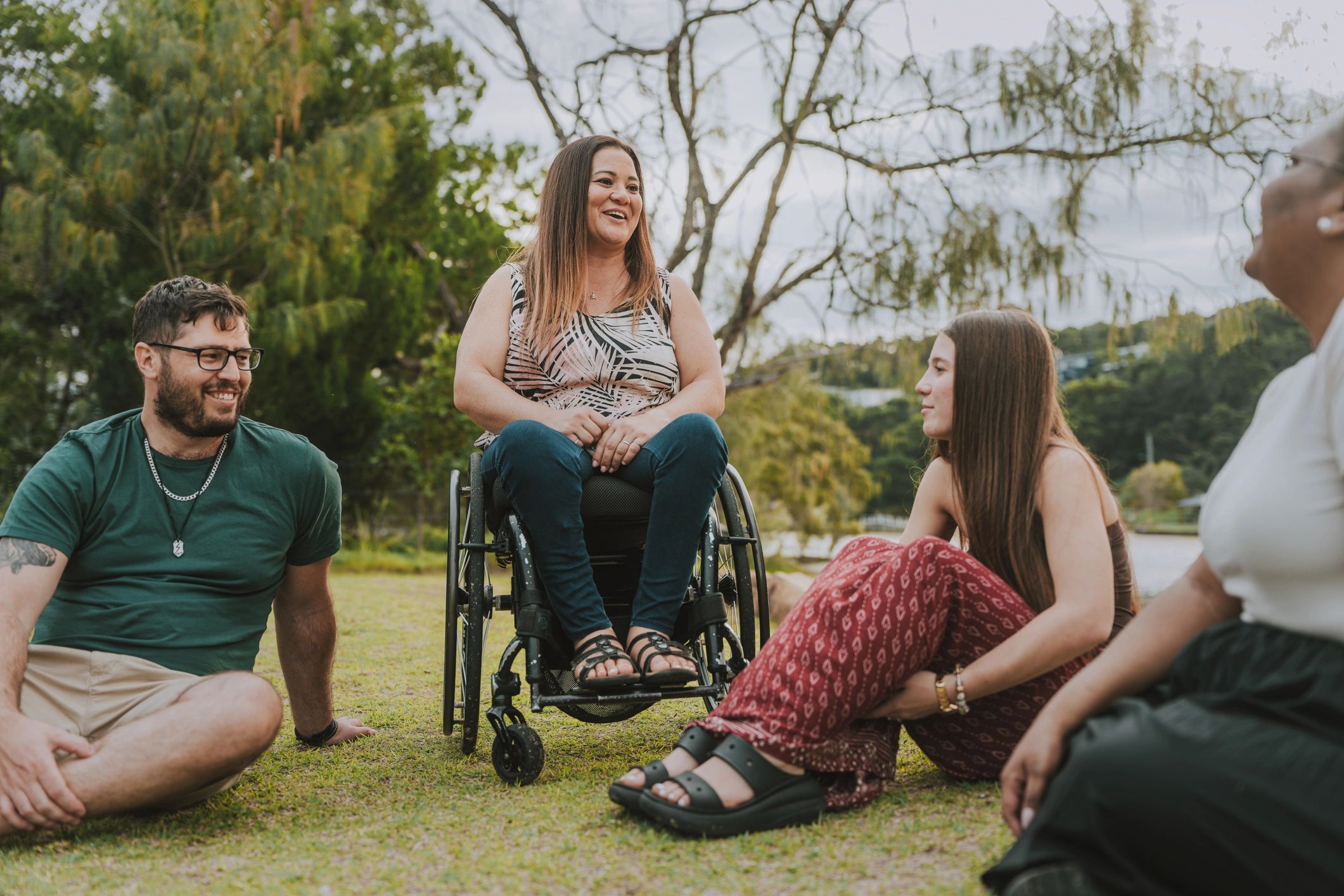 Woman using a wheelchair talking with friends in a park